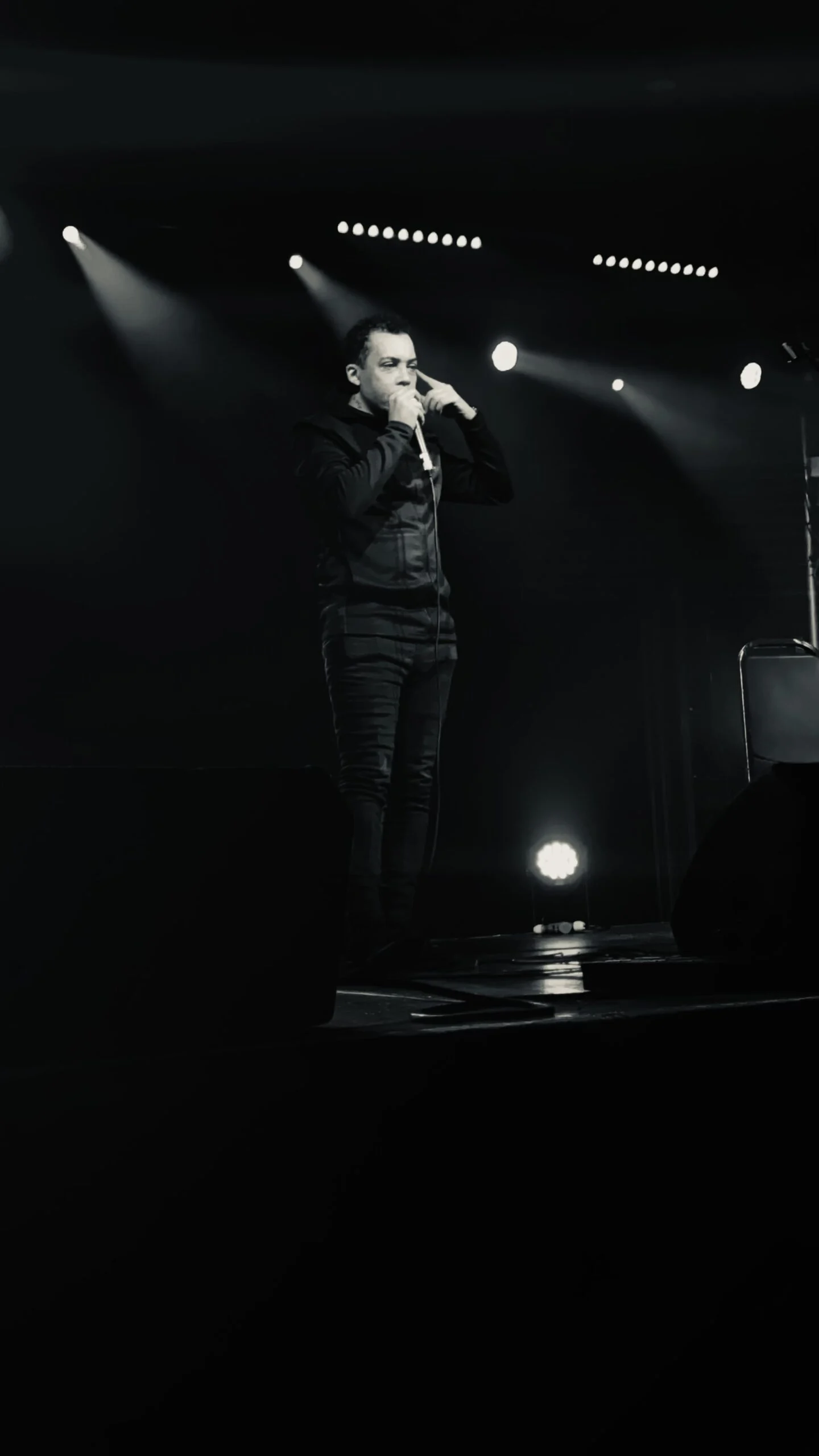 Majid image Majid standing on stage with a mic, black and white image.
